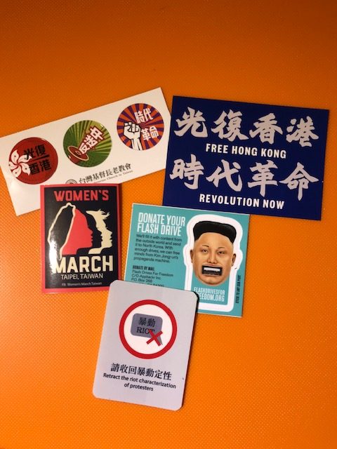 Stickers reading "Retract the riot characterization of protesters," "Women's March Taipei, Taiwan," "Free Hong Kong, Revolution Now," Donate your flash drive to be sent to North Korea filled with content challenging propaganda, and "Oppose the Extradition Law"