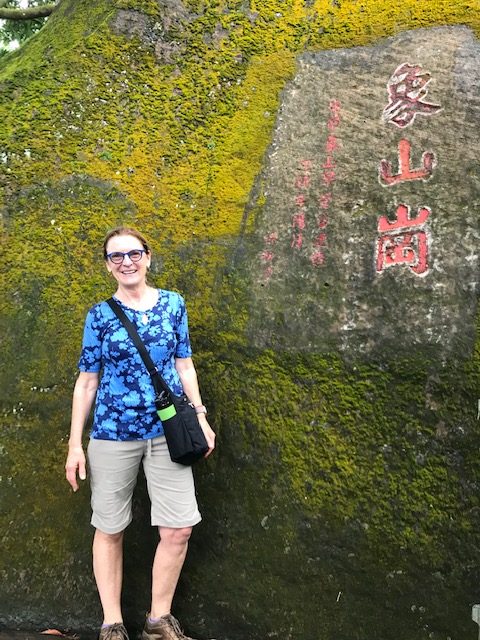 Jeanne Neumann in front of a mossy rock.