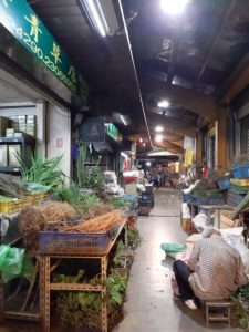 A narrow, roofed passageway lined with boxes of herbs.
