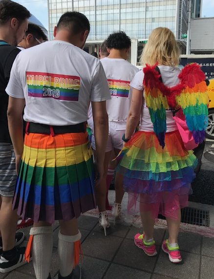 Man and woman in rainbow kilts and wings.