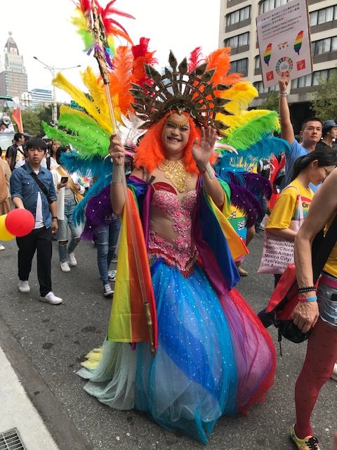 Man in a spectacular gown and drown, smiling and waving.