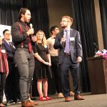 Two young men speaking on stage.
