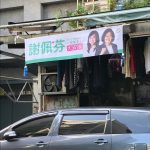 A campaign poster hanging over a line of laundry.