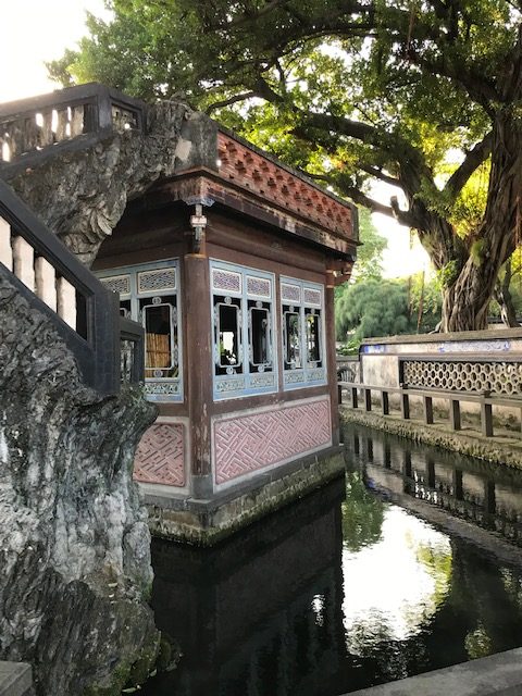 A square building in the middle of a pond.