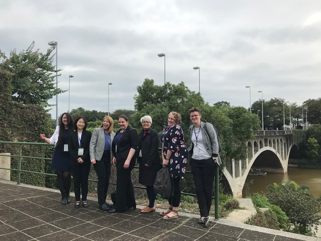 A group of women in front of a bridge.