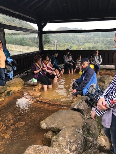 People soaking their feet in a hot spring pool.