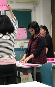 Detail of previous photo showing a woman putting ballots in piles on a table.